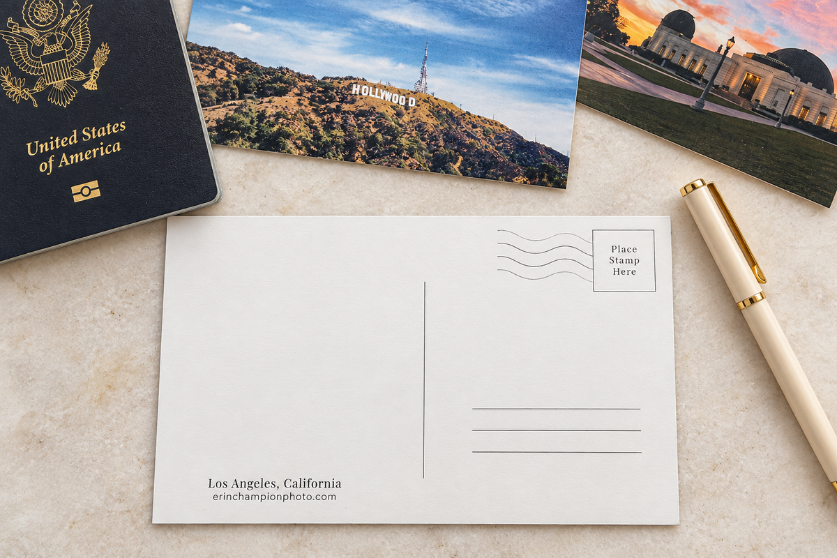 Back of Los Angeles postcard with Hollywood Sign, passport and pen on marble table